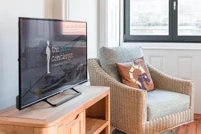 a living room with a tv and a wicker chair at GuestReady - Prince's Palace - HighLife in Porto