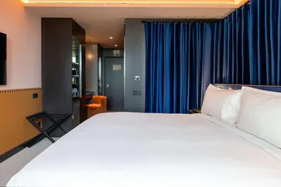 a bedroom with a large white bed and a chair at Cenica Porto Hotel, Curio Collection By Hilton in Porto