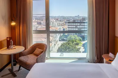 a dining room with a table and green chairs at Cenica Porto Hotel, Curio Collection By Hilton in Porto