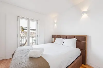 a white bedroom with a large bed and a window at GuestReady - Over the Bridge in Porto