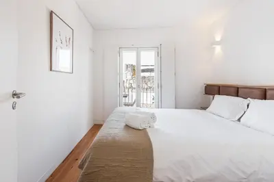 a white bedroom with a large bed and a window at GuestReady - Over the Bridge in Porto