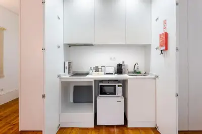 a small kitchen with white cabinets and a microwave at Almada e Fado in Porto