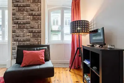 a living room with a black couch with a red pillow at Almada e Fado in Porto