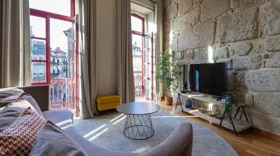 a living room with a stone wall and a table at Mouzinho's Place by LovelyStay in Porto