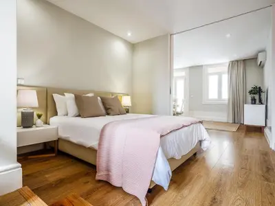 a white bedroom with a large bed and wooden floors at Oporto View Apartments in Porto