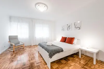 a white bedroom with a bed and a chair at GuestReady - Hospitality Atrium - Leite Residence in Vila Nova de Gaia