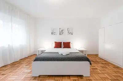 a white bedroom with a bed and two tables at GuestReady - Hospitality Atrium - Leite Residence in Vila Nova de Gaia