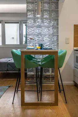 a dining table with green chairs in a room at ApartmentsPorto - Apartamento Belas Artes in Porto