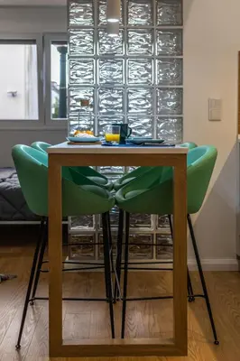 a wooden table with green chairs in a room at ApartmentsPorto - Apartamento Belas Artes in Porto