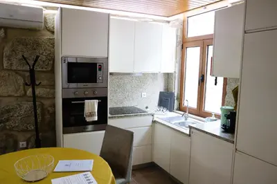 a kitchen with white cabinets and a table and a sink at Boavista Rustic House in Porto