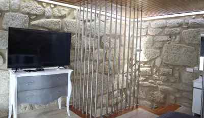 a television on a stand in front of a stone wall at Boavista Rustic House in Porto