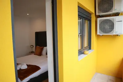 a yellow room with a bed and a window at Francos Family House in Porto