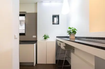 a kitchen with white cabinets and black counter tops at Host Wise - Cozy House w Balcony in Porto