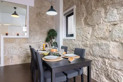 a dining room table with chairs and a stone wall at Host Wise - Cozy House w Balcony in Porto