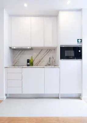 a white kitchen with white cabinets and appliances at Grandma aparts in Porto