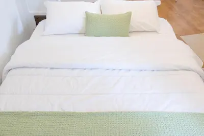 a white bed with white sheets and a green pillow at Grandma aparts in Porto