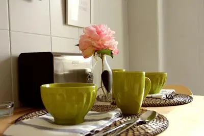 a table with three green cups and a flower in a vase at Lulapartment in Porto