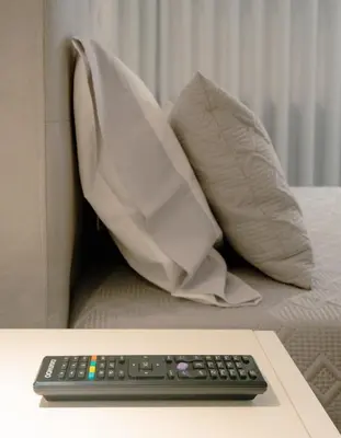 a remote control sitting on top of a bed with pillows at The Cale - Antero de Quental - 21 in Porto