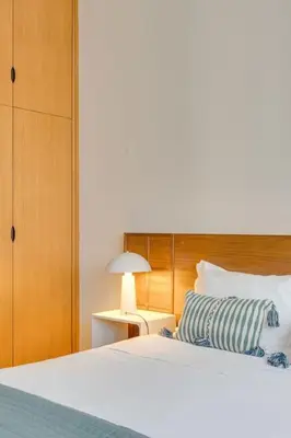 a bedroom with a white bed with a wooden headboard at Julio Dinis Studio in Porto