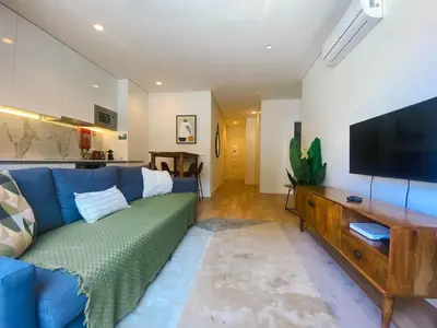 a living room with a blue couch and a flat screen tv at Paraíso E in Porto
