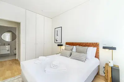 a white bedroom with a large white bed and a bathroom at Paraíso E in Porto