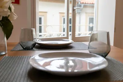 a table with a plate and two glasses on it at A Window to Porto - Premium Studio at Clérigos Tower in Porto