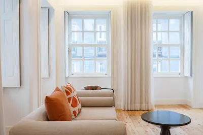 a living room with a couch and two windows at Feel Porto Clerigos Charm Flats in Porto