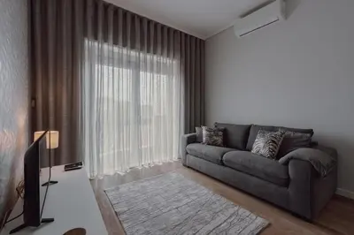 a living room with a couch and a large window at 1BR w/ AC near Palácio de Cristal in Porto