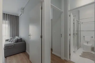 a white bathroom with a couch and a sink at 1BR w/ AC near Palácio de Cristal in Porto