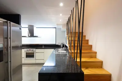 a kitchen with a black counter and a staircase at Trindade Premium Suites & Apartments in Porto