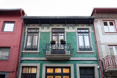 a green brick building with windows and a balcony at Trindade Premium Suites & Apartments in Porto