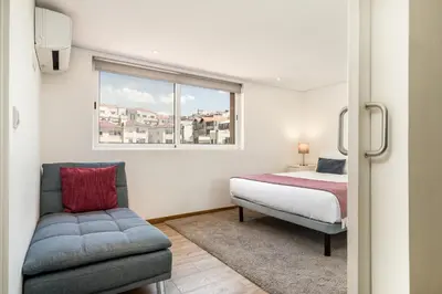 a bedroom with a bed and a chair and a window at Apartment Bolhao Market by Sweet Porto in Porto