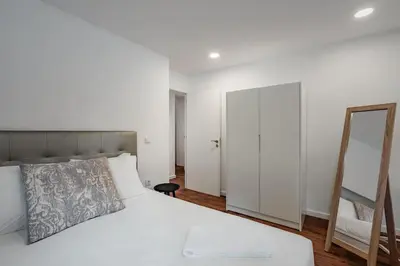 a bedroom with a white bed and a mirror at Bonfim Apartment by Best2Stay in Porto