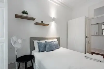 a white bedroom with a large bed with blue pillows at Bonfim Apartment by Best2Stay in Porto