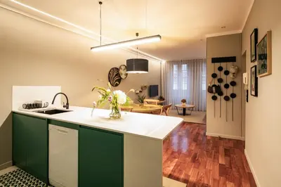 a kitchen with green cabinets and a living room at Porto Insight Apartments- with balcony in Porto