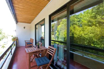 a balcony with a wooden table and chairs and a large window at VIVA Belos Ares in Porto