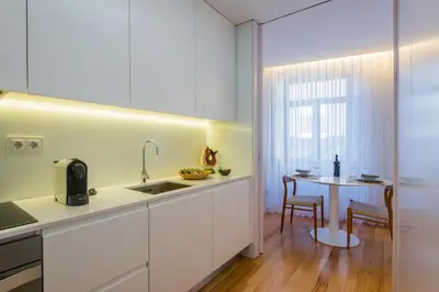 a kitchen with white cabinets and a small table at Domum in Porto