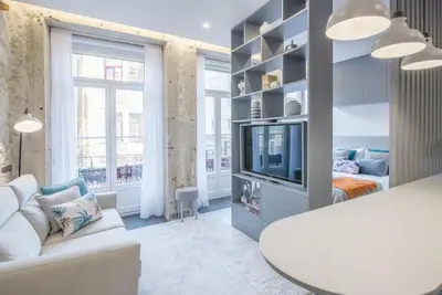 a living room with a white couch and a tv at Ribeira Apartments Baixa in Porto