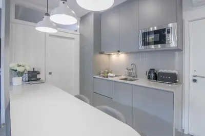 a white kitchen with a sink and a microwave at Ribeira Apartments Baixa in Porto
