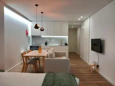 a living room with a table and a kitchen at Fontinha House in Porto