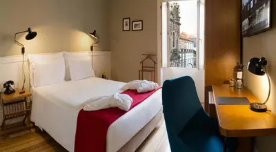 a bedroom with a white bed and a desk and a window at Porto A.S. 1829 Hotel in Porto