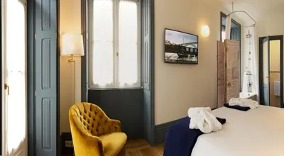 a room with a bed and a yellow chair at Porto A.S. 1829 Hotel in Porto