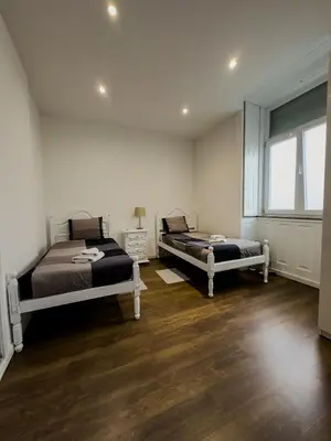 two beds in a room with wooden floors and a window at Antero de Quental Studios 2 in Porto