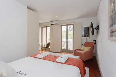 a white bedroom with a bed and a chair at Liiiving in Porto - Trindade Deluxe Studios in Porto