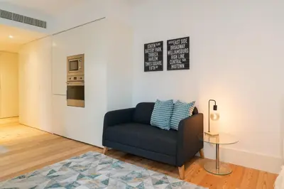 a living room with a blue chair and a table at Urban Stylish Studio with Balcony in Porto