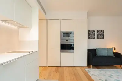 a kitchen with white cabinets and a black couch at Urban Stylish Studio with Balcony in Porto