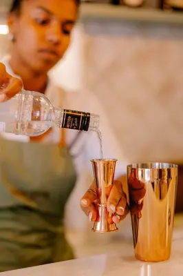a woman pouring a drink from a bottle into a cup at Casa Zogbi Hotel in Porto