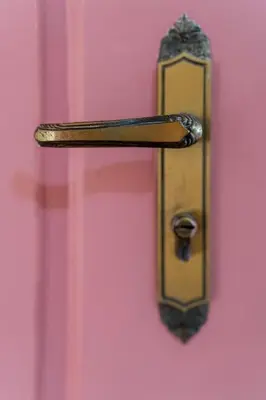 a gold door handle on a pink door at The Charm Bonfim OPO in Porto
