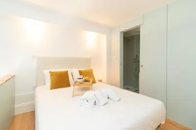 a white bedroom with a large white bed with yellow pillows at Formosa Studios by Upperground in Porto