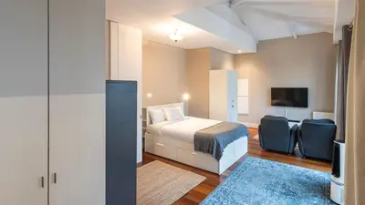 a bedroom with a bed and two chairs and a tv at Cardosas Spacious Studio by LovelyStay in Porto